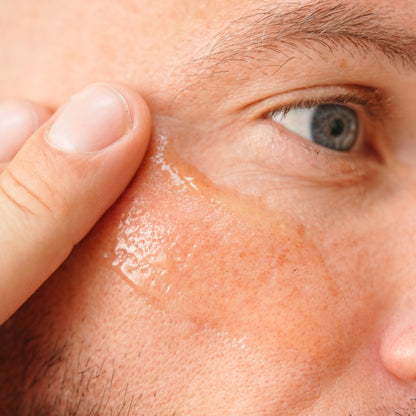 Close-up of a man applying cream to his forehead
